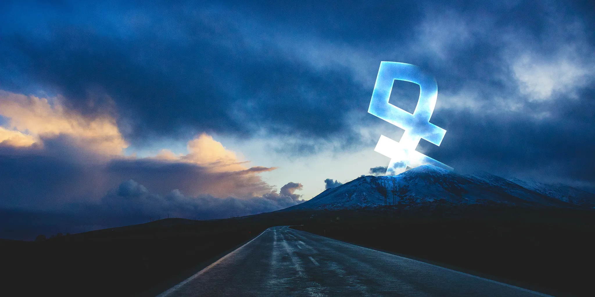 A mountain road view with the bright Yaad logo behind the mountains, glowing in the dark.